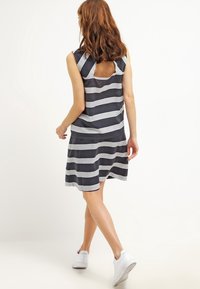 Vestido a rayas en azul marino y blanco, con mangas cortas, escote en la espalda y falda acampanada. Confeccionado en tela ligera.