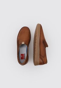 Zapatos marrones de tipo slip-on con una superficie texturizada, suela de goma y acolchado interior. Presentan un pequeño logotipo en el lateral y un diseño perforado.