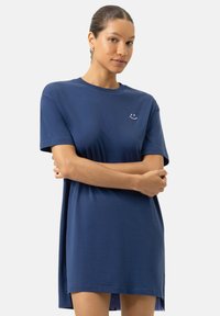 Robe t-shirt en coton bleu marine à coupe décontractée, manches courtes et visage souriant brodé sur la poitrine. Fentes latérales à l'ourlet.