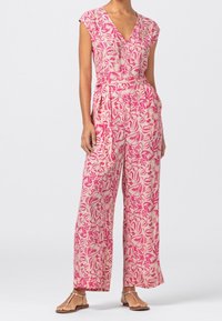 Blommig jumpsuit med korta ärmar, V-ringning, vida ben, i rosa och krämfärgade toner, som har en cinchad midja och en mjuk tygtextur.