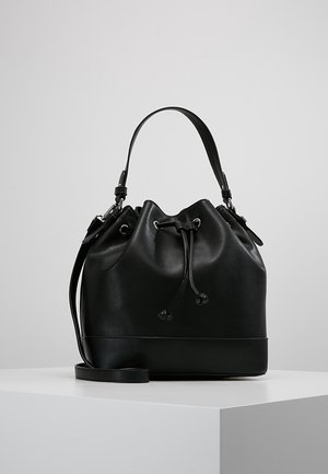 Sac seau en cuir noir avec fermeture à cordon, poignée courte et bandoulière amovible sur un socle blanc sur fond gris.