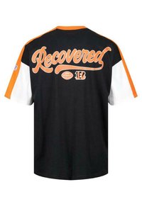 Mustapohjainen ja oranssipainotteinen lyhythihainen t-paita, jossa selässä on valkoisella käsinkirjoitettu teksti "Recovered" sekä pyöreä logo ja oranssi numero "13".