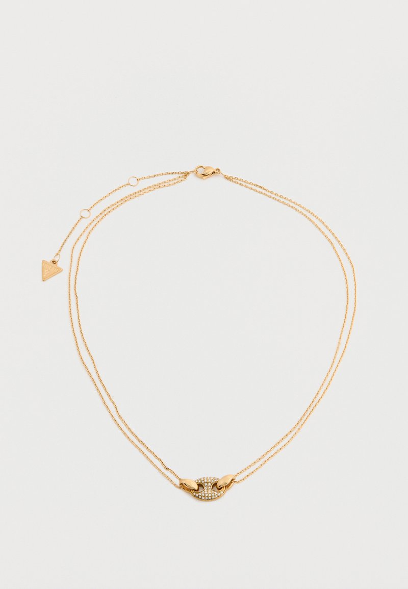 Λεπτό διπλό χρυσό κολιέ με οβάλ μενταγιόν διακοσμημένο με μικρά διαφανα κρύσταλλα και ένα μικρό τρίγωνο γούρι κοντά στο κούμπωμα.