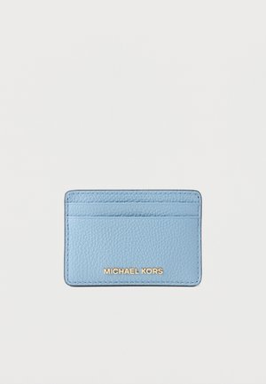 Porte-cartes en cuir bleu clair texturé avec trois emplacements pour cartes et logo Michael Kors doré sur le devant, sur fond blanc.