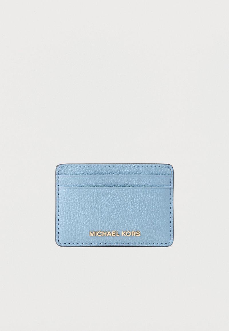 Porte-cartes en cuir bleu clair texturé avec trois emplacements pour cartes et logo Michael Kors doré sur le devant, sur fond blanc.