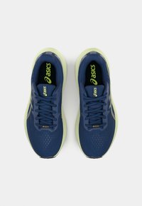 Běžecké boty Asics s tmavě modrým syntetickým svrškem, světlou zelenou podrážkou, síťovinovými panely a plochými tkaničkami. Výrazné logo na jazyku a na boku.