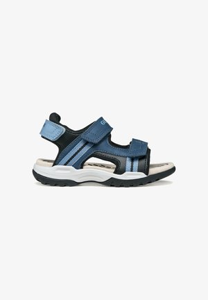 Sandales bleu foncé et noires avec des sangles en velcro, une semelle intérieure rembourrée et une semelle intermédiaire blanche, dotées de semelles extérieures en caoutchouc noir texturé.