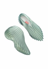 Sandalias translúcidas y texturizadas con un diseño ondulado en verde suave, con el logotipo de las marcas 'Melissa' y 'Diesel' en rojo en la planta.