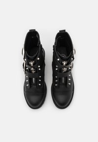 Stivali neri alla caviglia in pelle testurizzata, con borchie argentate, cinghie e cerniere per la chiusura. Design con punta arrotondata e suola piatta.