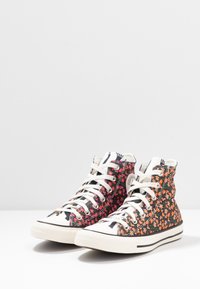 Sneakers alte con una base nera decorata da motivi floreali rosa e arancioni, lacci bianchi, punte in gomma e suola bianca.