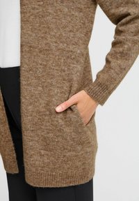 Cardigan in maglia marrone con una texture morbida, maniche lunghe, apertura frontale e tasche laterali, rifinito con polsini e orlo a coste.