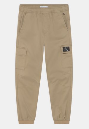 Beżowe spodnie typu cargo z elastycznym paskiem i mankietami, bocznymi kieszeniami oraz naszywką z logo Calvin Klein Jeans na prawej kieszeni.