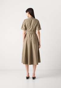 Khaki dress with a fitted bodice, short sleeves, and a flared midi-length skirt. Features a belted waist and smooth, lightweight fabric.