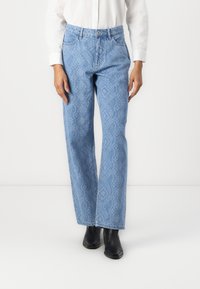 Lys blå denimjeans med slangeskinnmønster, rett ben-design, fem lommer og knappelukking, kombinert med svarte ankelstøvler.