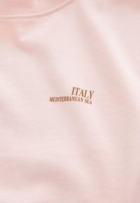 T-shirt en coton rose clair avec encolure arrondie. Porte les inscriptions "ITALY" et "MEDITERRANEAN SEA" imprimées en lettres dorées sur le devant.