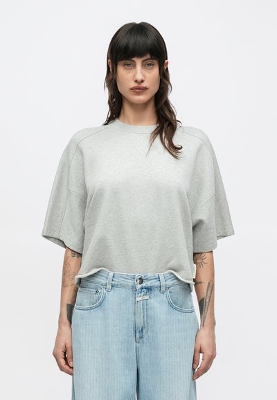 Light gray oversized t-shirt made of soft fabric, featuring a round neck and short, wide sleeves, paired with light blue denim jeans.
