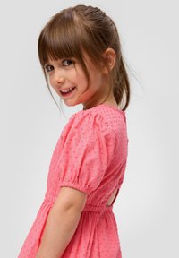 Rosa strukturiertes Kleid mit Puffärmeln, einer Knopfverschluss hinten und einer gerafften Taille. Der Stoff zeigt kleine erhabene Punkte für Details.