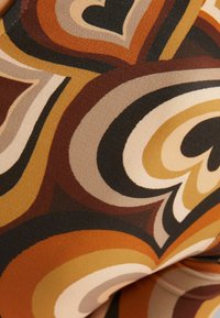 Patterned fabric featuring bold swirls in shades of brown, beige, and orange with smooth texture and a soft sheen.