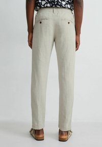 Pantalons en lin beige clair avec une jambe droite, une taille élastique et deux poches arrière avec des boutons bruns.