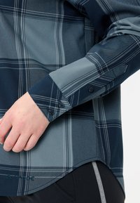 Camicia button-up con un motivo a quadri blu e grigio. Presenta un tessuto morbido, maniche lunghe e polsini a contrasto con dettagli botones.