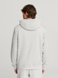 Felpa grigia in tessuto morbido, caratterizzata da un ampio cappuccio, polsini a coste e una vestibilità comoda. Texture liscia con un aspetto leggermente melangiato.