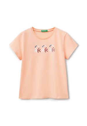 T-shirt color pesca realizzato in cotone morbido. Presenta un collo rotondo e maniche corte. Sul davanti ci sono tre figure stilizzate in blu e rosa.