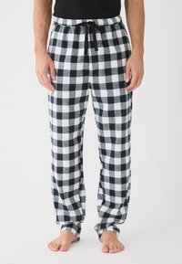 Svart og hvit rutete flanell pysjamasbukser med elastisk midje og snor. Myk tekstur, løs passform, og smale mansjetter.