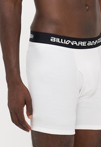 Boxeri albi din material ribbed, având un elastic negru la talie cu logo-ul alb "Billionaire Boys Club". Design ajustat cu lungime până la mijlocul coapsei.