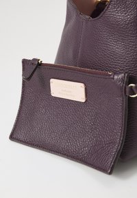 Borsa a tracolla in pelle viola con finitura testurizzata, dotata di una pochette rimovibile con zip e un'etichetta in hardware dorato. Fodera interna liscia.