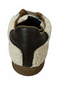 Zapatilla de cuero marrón con parte superior de textil blanco y esponjoso, con una forma redondeada y suela de goma texturizada.