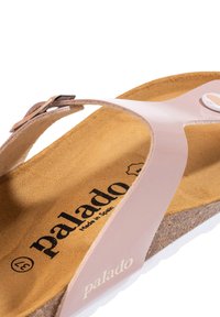 Palado sandal i rosa, med ett slätt övre rem, korkfotbädd med beige foder och vit texturerad sula. Märkt "Made in Spain."