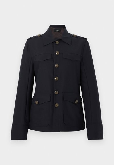 Μαύρο στρατιωτικού στυλ μπουφάν με μεγάλα χρυσά κουμπιά, επιλοφία στους ώμους, τέσσερις τσέπες με καπάκι και μυτερό γιακά.