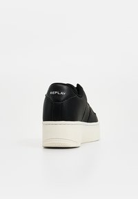 Basket en cuir noir texturé avec semelle plateforme blanche, marquage "REPLAY" sur le talon, vue de l'arrière sur fond blanc.