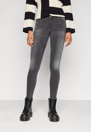 Grey skinny jeans with a faded finish, five-pocket design, and belt loops, paired with black lace-up boots and a black-and-white striped sweater.