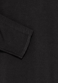 Tissu tricoté noir montrant une manche pliée avec une couture de poignet côtelée et un matériau à texture fine.