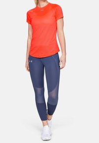 Röd idrottströja med kort ärm i kombination med marinblå leggings med meshinlägg. Slät, lättviktsmaterial med en figurnära design.