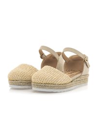 Beige Espadrilles mit gewebter strohähnlicher Vorderseite, elastischem Riemen und juteumwickelter Sohle. Solider, hellfarbener Textilrücken mit Schnallen-Detail.