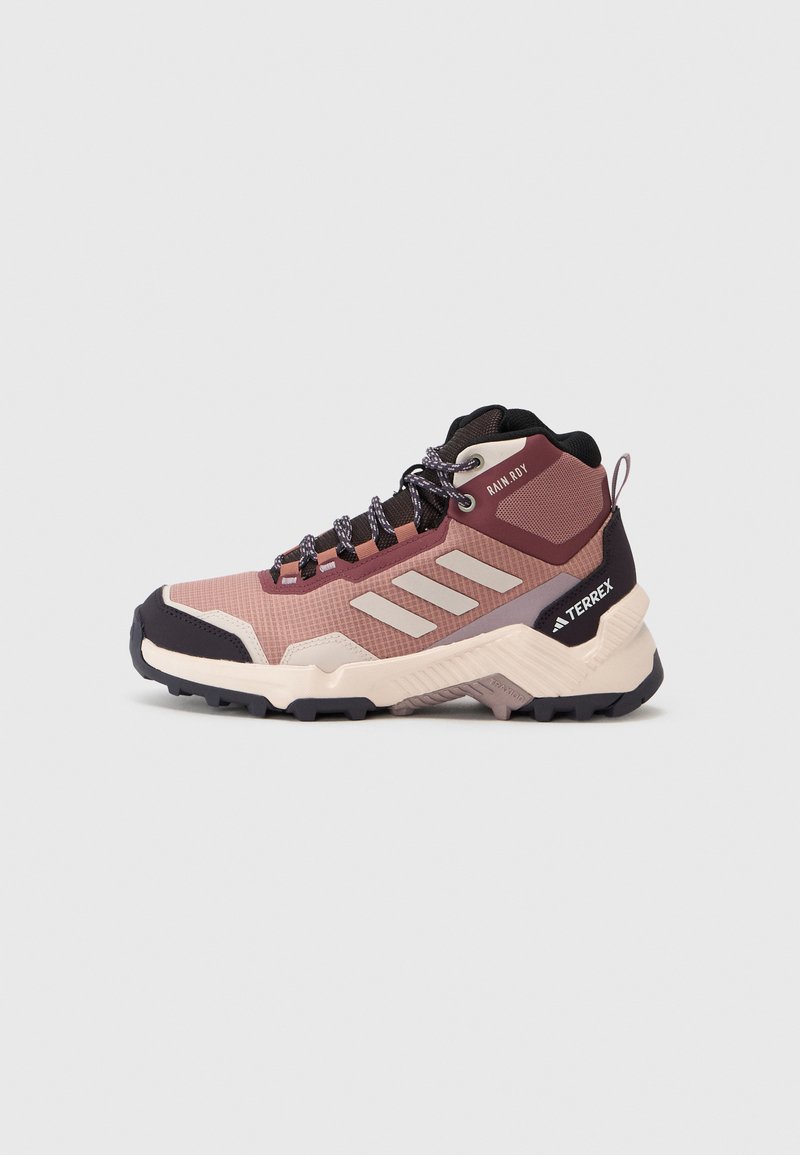 Hiking boot in pink and dark purple, featuring mesh upper, rubber sole, textured patterns, and reinforced ankle support.