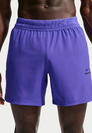 Mannelijke torso draagt paarse Nike Pro shorts met elastische tailleband en klein zwart Nike-logo op het linkerbeen.