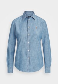 Ljusblå denimskjorta med långa ärmar, knappstängning fram och spetskrage. Litet broderat märke p å vänster bröst. Slen textur.