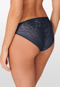 Hochtaillierte marineblaue Panty mit floralem Spitzenoverlay, glatten Seitenteilen und gerafftem Rücken für zusätzliche Textur und Details.