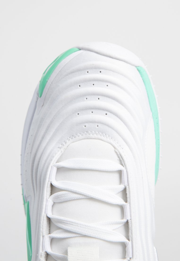 Zapatilla blanca con parte superior texturizada, que presenta detalles en verde y una punta redonda. Los cordones son blancos, con perforaciones para ventilación.