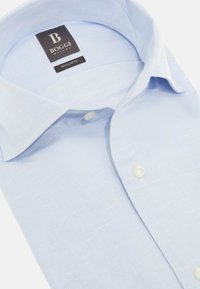 Camicia azzurra a fantasia con taglio regolare. Collo a bottoni, bottoni bianchi e un'etichetta con "Boggi Milano." Texture liscia.