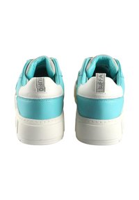 Baskets turquoises et blanches avec une épaisse semelle blanche, en cuir texturé, un col rembourré et un label de marque bien visible sur le talon.