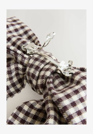 Clip pentru păr din material cu un model pătrat în nuanțe de maro și crem, cu o clemă metalică, având o textură netedă și un design torsadat.