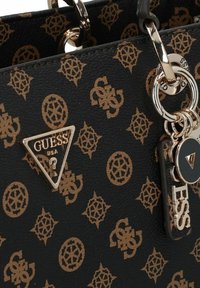 Borsa nera con finitura testurizzata, caratterizzata da un motivo a logo dorato ripetuto, un emblema triangolare dorato del marchio e dettagli in metallo decorativo.
