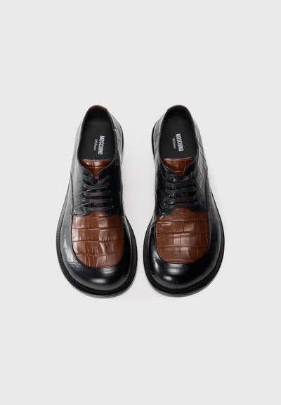 Black and brown leather shoes featuring a crocodile texture on the brown section, rounded toe, and lace-up design.