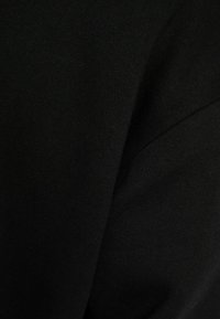 Svart tyg med en slät textur och en subtil glans. Närbild som framhäver den rika färgen och den mjuka ytan. Inga mönster eller detaljer.