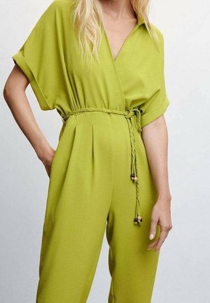 Combinaison verte à manches courtes avec un col en V et une taille ceinturée. Elle comporte un cordon tressé avec des accents en bois, fabriquée dans un tissu léger.