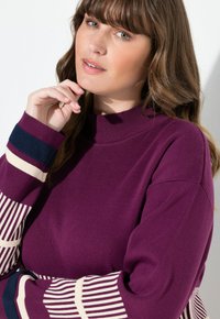 Maglione viola a costine con collo alto e maniche a righe in crema e blu navy, caratterizzato da una vestibilità comoda e una texture morbida.